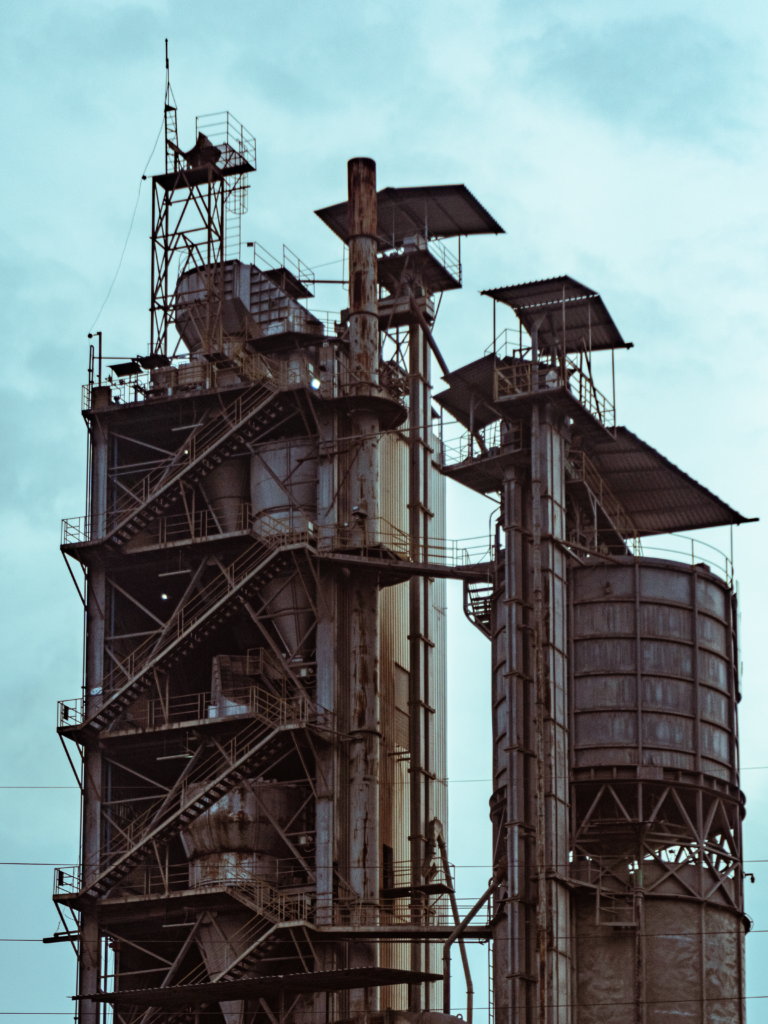 A close-up view of industrial factory towers with a clear blue sky background.