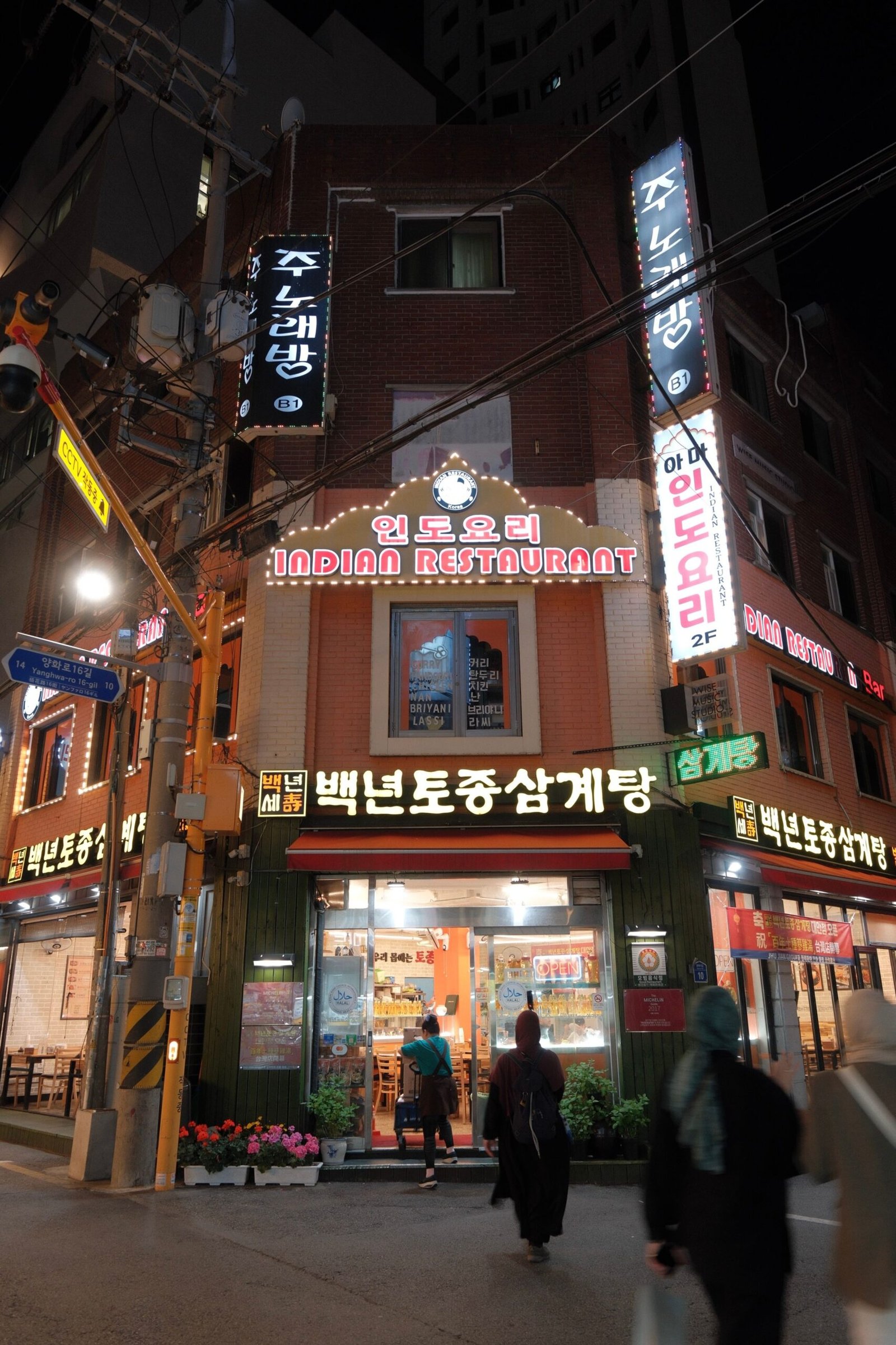 Night view of a bustling street with an Indian restaurant in South Korea, showcasing cultural diversity.